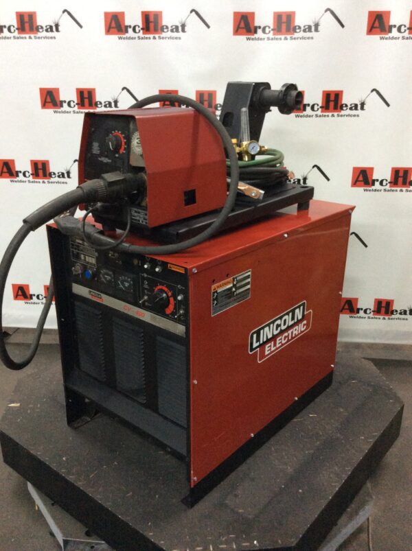 A Lincoln Idealarc CV-400 MIG Welder on a stand with a hose attached to it.