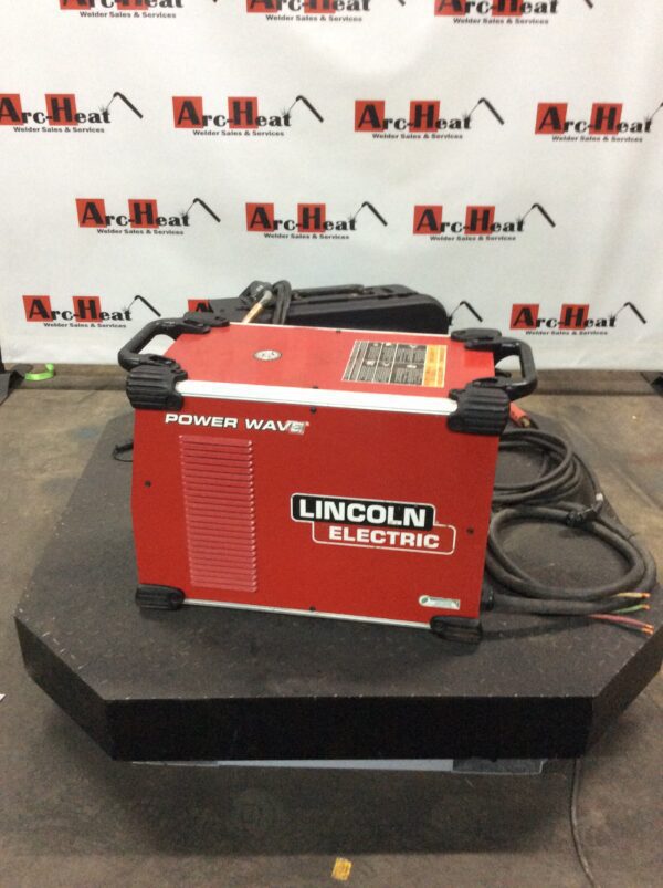 A lincoln electric power wave welder is sitting on top of a table.