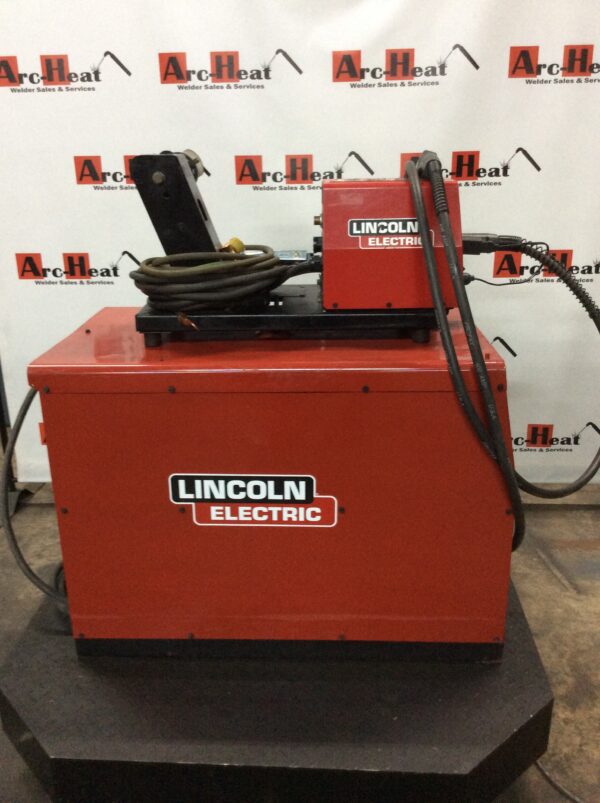 A lincoln electric wire feeder sitting on top of a red box.