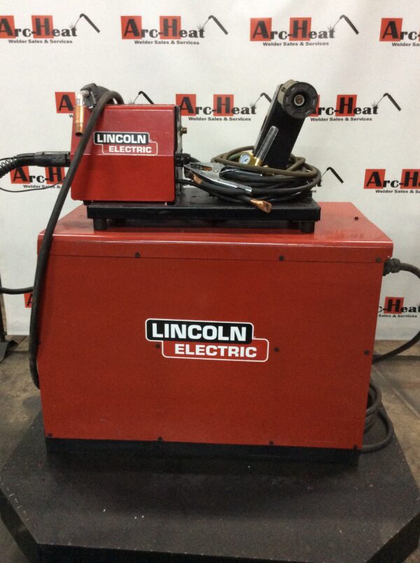 A lincoln electric welding machine sitting on top of a box.